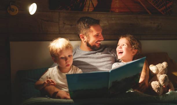 Père lisant un livre a ses deux fils avant le coucher